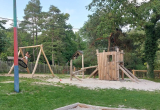 Speelplein met houten schommel en klimtoren op Camping Le Roptai, vakantiepark in Namen, België.
