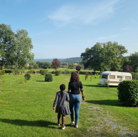 Dos personas caminan sobre césped cerca de una caravana en Camping Le Roptai en Namur, Bélgica.