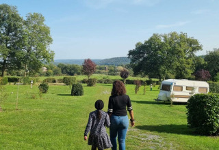 Due persone camminano sull’erba verde vicino a una roulotte al Camping Le Roptai, Namur, Belgio.
