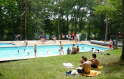 Feriecampister nyder swimmingpoolen omgivet af træer ved Camping Le Roptai i Namur, Belgien.