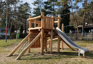 Houten speeltuig met glijbaan op Camping Le Roptai in Namen, België, omringd door groen en bomen.