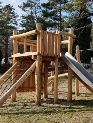 Aire de jeux en bois avec toboggan au Camping Le Roptai à Namur, Belgique, entourée de verdure.
