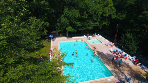 Luftaufnahme eines Schwimmbads mit Gästen, umgeben von Bäumen im Camping Le Roptai, Namur, Belgien.