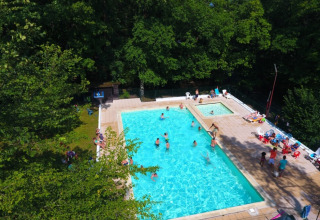 Vue aérienne d'une piscine avec des gens, entourée d'arbres au Camping Le Roptai à Namur, Belgique.