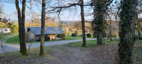 Vista del camping Le Roptai en Namur, Bélgica, con árboles, una cabaña y paisajes primaverales.