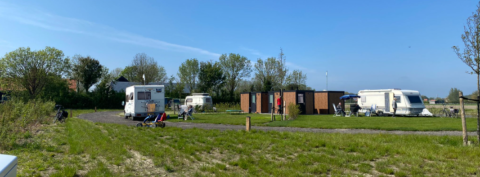 Caravanas y autocaravanas en Minicamping Hofstede Zonnevliet en un día soleado en Zeeland, Países Bajos.