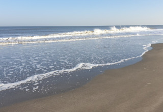Rustig zandstrand met zachte golven aan Minicamping Hofstede Zonnevliet in Zeeland, Nederland.