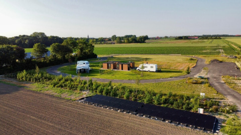 Minicamping Hofstede Zonnevliet en Zelanda, Países Bajos, con paneles solares, caravanas y campos verdes rurales.