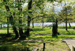 Vista verde sobre el campo de minigolf y parque junto al lago en Camping Montard, Nouvelle-Aquitaine, Francia.