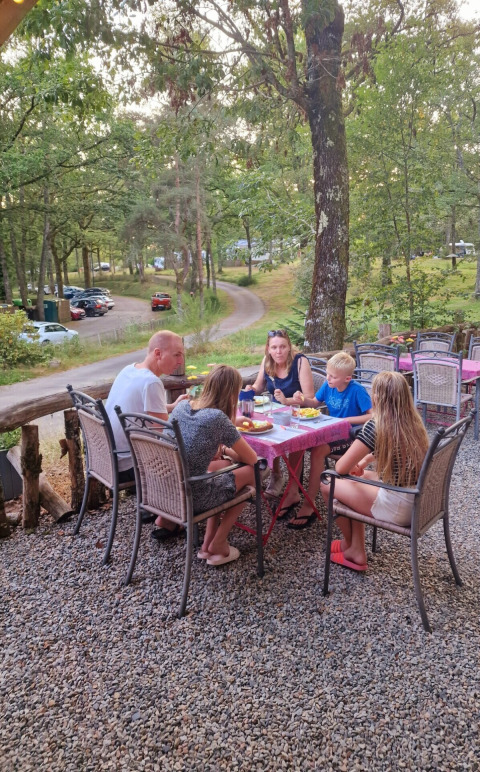 Gezin eet samen buiten bij Camping Montard, een vakantiepark in Nouvelle-Aquitaine, Frankrijk.