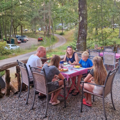 Familia compartiendo una comida al aire libre en Camping Montard, parque vacacional en Nouvelle-Aquitaine, Francia.