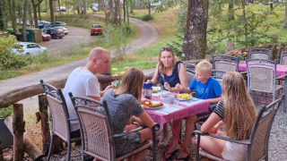 Familia compartiendo una comida al aire libre en Camping Montard, parque vacacional en Nouvelle-Aquitaine, Francia.