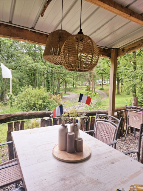 Area pranzo all’aperto al Camping Montard in Nouvelle-Aquitaine, Francia, con bandiere francesi sul tavolo.