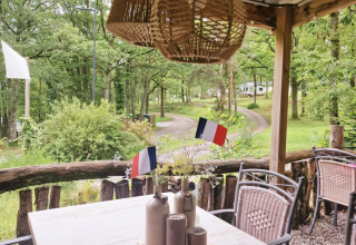 Zona de comedor exterior en Camping Montard, Nouvelle-Aquitaine, Francia, con banderas francesas en la mesa.