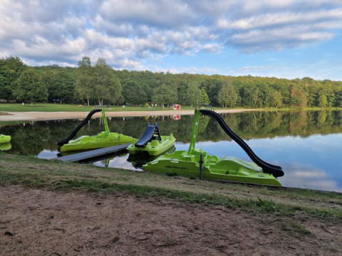 Green pedal boats with slides on a lake at Camping Montard holiday park in Nouvelle-Aquitaine, France.