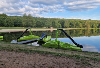 Green pedal boats with slides on a lake at Camping Montard holiday park in Nouvelle-Aquitaine, France.