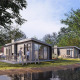Moderne lodge ved vandet i Zypendaal Comfort, Veluwepark de Bosgraaf, Holland, omgivet af træer.
