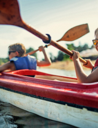 Dos niños con chalecos salvavidas remando en kayak cerca de Lamongerie, Nouvelle-Aquitaine, Francia, en un día soleado.