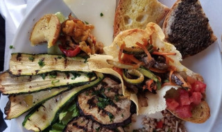 Un piatto di antipasti italiani con verdure grigliate, formaggio, pane e insalate al Camping Il Collaccio.