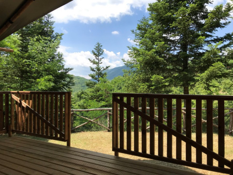 Vista desde una terraza de madera con árboles y montañas en Camping Il Collaccio, Umbría, Italia.