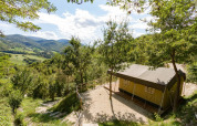 Udsigt over telte og bjerge hos Camping Il Collaccio i Umbrien, Italien, omgivet af grønne bakker.