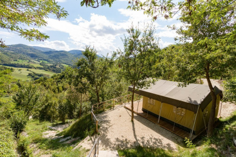 Tienda de campaña en Camping Il Collaccio, Umbría, Italia, rodeada de colinas y naturaleza verde.