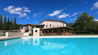 Vista della piscina e della villa in pietra al Camping Il Collaccio, parco vacanze in Umbria, Italia.