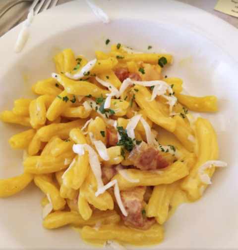 Un piatto di pasta fresca con salsa cremosa e pancetta, servito vicino a Preci in Umbria, Italia.