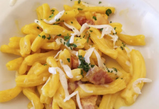 Ein Teller frische Pasta mit cremiger Sauce und Speck, serviert nahe Preci in Umbrien, Italien.