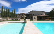 Udsigt til swimmingpool og stenhus på Camping Il Collaccio feriepark i det naturskønne Umbria, Italien.