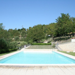 Piscina all'aperto presso Camping Il Collaccio, parco vacanze in Umbria, Italia, circondata dal verde.