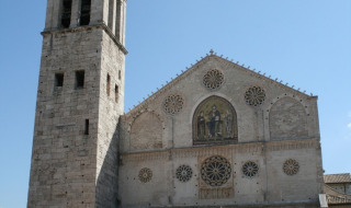 Facciata e campanile di una chiesa storica vicino a Preci, Umbria, Italia, sotto un cielo limpido