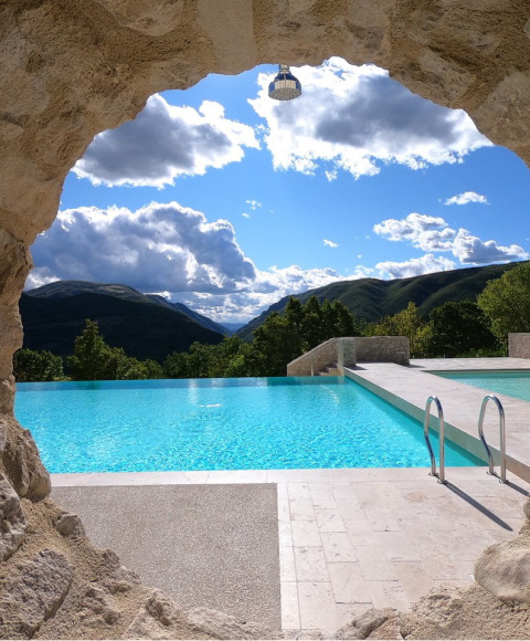 View from a cave looking out over the pool at Camping Il Collaccio, with mountains beyond in Umbria, Italy.