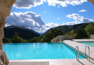 View from a cave looking out over the pool at Camping Il Collaccio, with mountains beyond in Umbria, Italy.