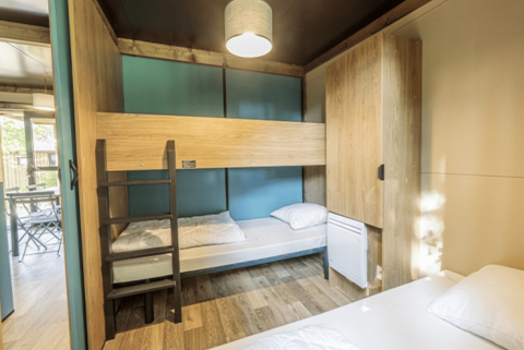 Interiøret af Chalet Evasion ved Camping de Lyon i Frankrig viser køjesenge og et lyst, moderne design.