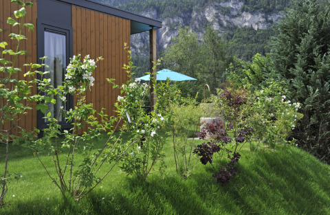 Zicht op een lodge bij Mountain Lodges, omgeven door een groene tuin en bergen op de achtergrond.