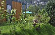 Udsigt til en hytte ved Mountain Lodges omgivet af frodig have og bjerge i baggrunden.
