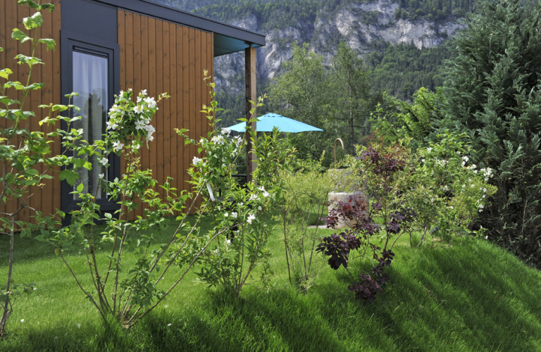 Aussicht auf eine Hütte bei Mountain Lodges, umgeben von Garten und Bergen im Hintergrund.