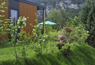 Udsigt til en hytte ved Mountain Lodges omgivet af frodig have og bjerge i baggrunden.