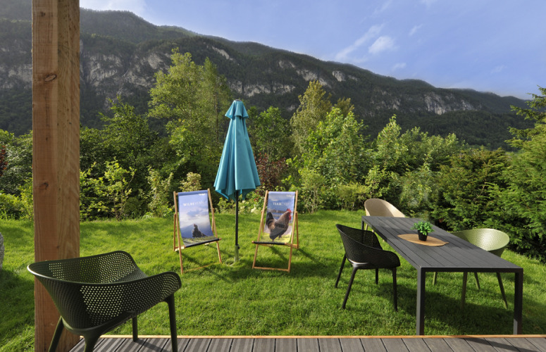 Terrasse der Mountain Lodges mit Stühlen, Tisch, Sonnenschirm und Blick auf Berge und Wälder.