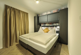 Camera da letto ai Mountain Lodges con letto matrimoniale, armadi moderni e tende color oro beige.