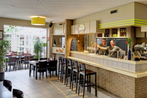Area bar al Camping Kempen, parco vacanze ad Anversa, Belgio, con personale cordiale dietro al bancone.