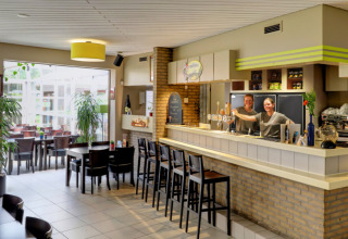 Zona de bar en Camping Kempen, parque vacacional en Amberes, Bélgica, con personal amable tras la barra.