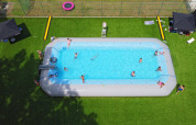 Ferieglade mennesker nyder en stor, oppustelig swimmingpool på Camping Kempen i Antwerpen, Belgien.