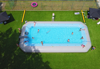 Ferieglade mennesker nyder en stor, oppustelig swimmingpool på Camping Kempen i Antwerpen, Belgien.
