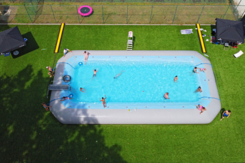 Ferieglade mennesker nyder en stor, oppustelig swimmingpool på Camping Kempen i Antwerpen, Belgien.