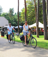 Mensen fietsen door een groen gebied op vakantiepark Camping Kempen in Antwerpen, België, omringd door bomen.