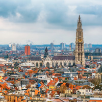 Vista panorámica de Amberes con sus edificios históricos, tejados y torres de iglesia bajo un cielo nublado.