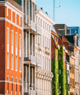 Fila de edificios clásicos de colores y vegetación en una calle soleada de Lichtaart, Amberes, Bélgica.