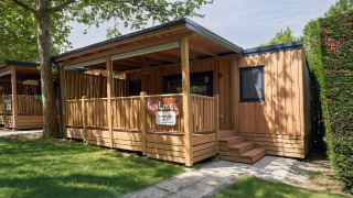 Chalet en bois SunLodge Katsura avec terrasse couverte, pelouse verte, et ambiance naturelle tranquille.